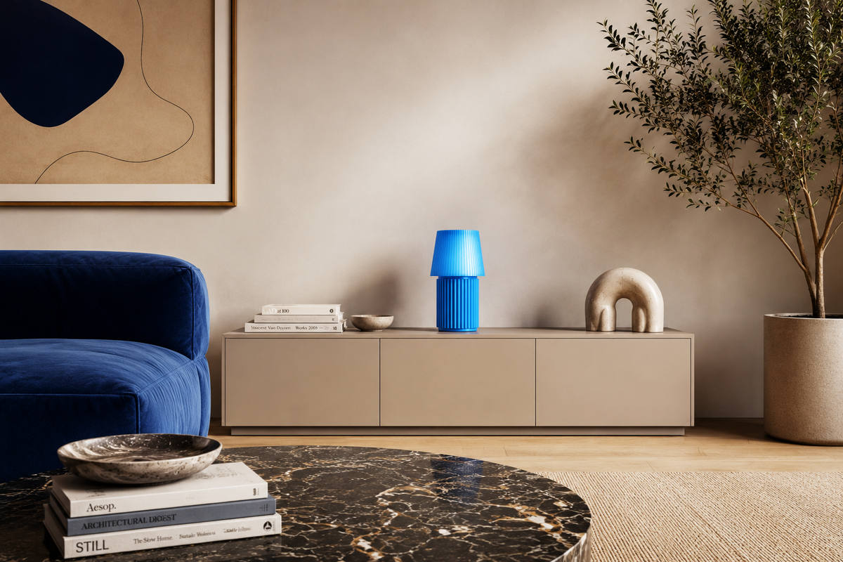 Kono Sky table lamp by Lempori displayed on a sideboard in a modern living room with blue accents and warm ambient lighting.